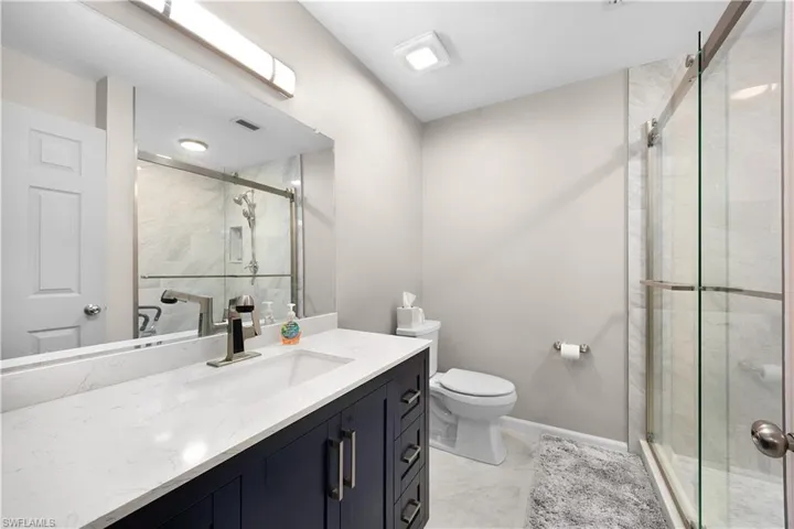 Full bath with vanity, a marble finish shower, and light marble finish flooring