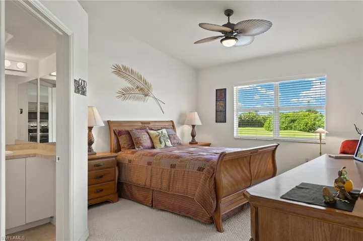 Bedroom with ceiling fan, light carpet, and connected bathroom