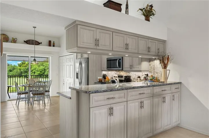 Kitchen featuring light tile patterned floors, tasteful backsplash, stainless steel appliances, and stone counters