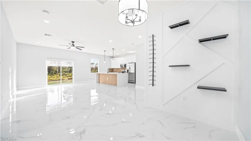 Unfurnished living room with recessed lighting, light marble finish flooring, a chandelier, and a ceiling fan