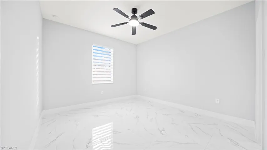 Empty room featuring marble finish floors and ceiling fan