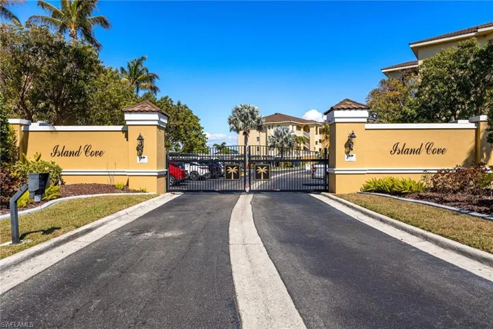 View of asphalt road featuring a gated entry, a gate, and curbs