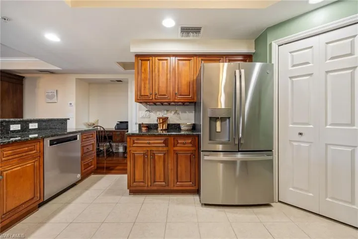 Kitchen featuring stainless steel appliances, dark stone counters, recessed lighting, wood finish cabinetry, and light tile patterned floors