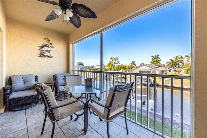 Sunroom / solarium featuring ceiling fan, a balcony, a water view, and outdoor dining area
