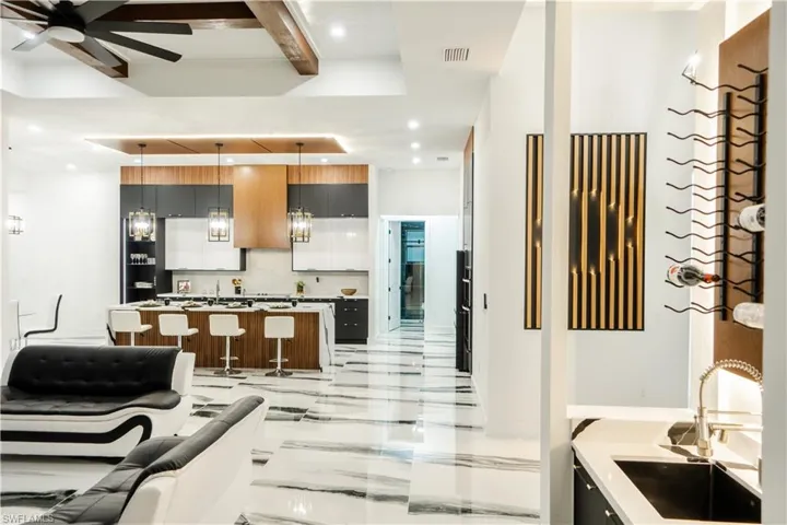 Kitchen featuring light tile flooring, backsplash, ceiling fan, beamed ceiling, and sink