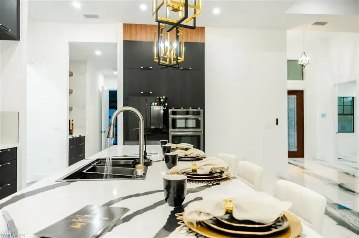 Kitchen featuring double oven, hanging light fixtures, sink, and an inviting chandelier