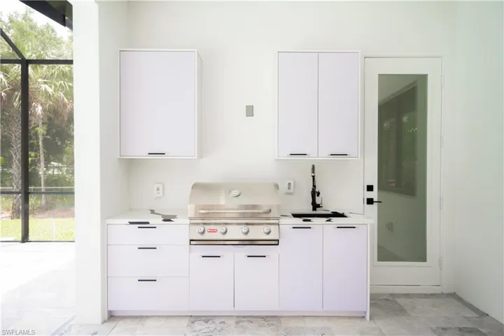 Kitchen with white cabinets, sink, and light tile flooring