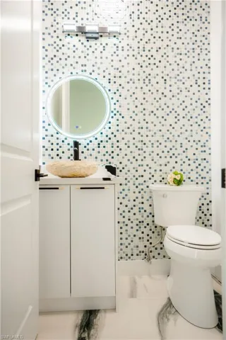 Bathroom with tile walls, tile floors, vanity, and toilet