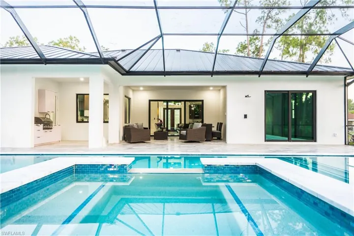 View of swimming pool featuring outdoor lounge area, glass enclosure, a patio area, and a grill