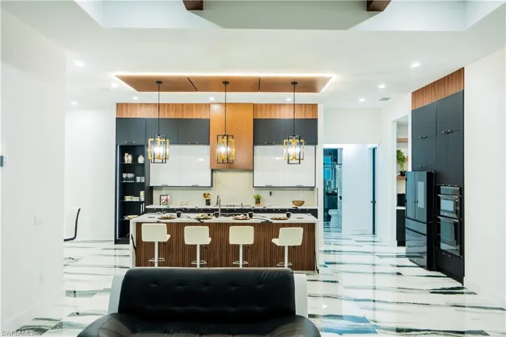 Kitchen featuring a kitchen island with sink, a breakfast bar, light tile flooring, and backsplash