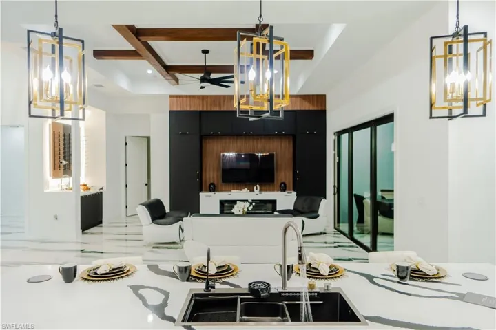 Kitchen with sink, coffered ceiling, ceiling fan, and pendant lighting