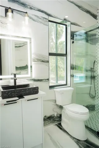 Bathroom featuring an enclosed shower, toilet, and vanity