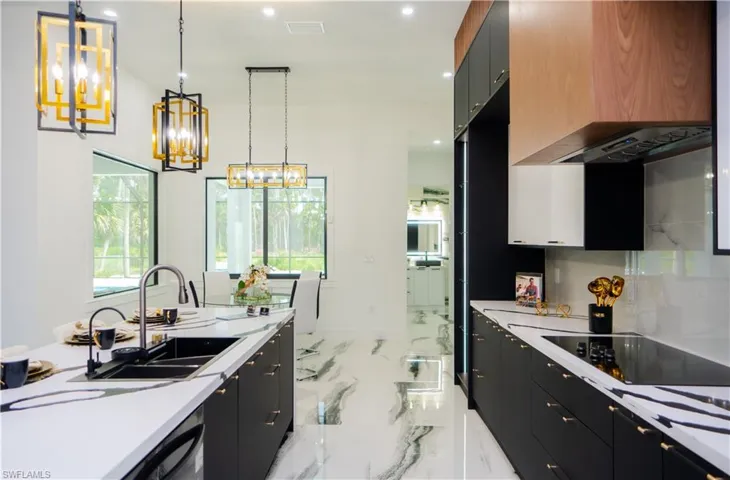 Kitchen featuring sink, black electric stovetop, light tile floors, and pendant lighting