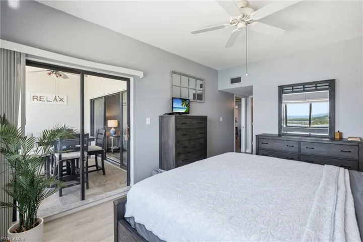 Spacious room featuring light-toned walls, wood-finish flooring, and a ceiling fan - Virtually Edited Image