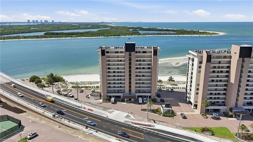 Multi-story building directly fronting a sandy beach and expansive body of water - Virtually Edited Image
