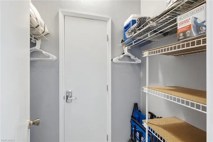 Storage closet featuring white wire shelving, a hanging rod, and light gray wall paint - Virtually Edited Image