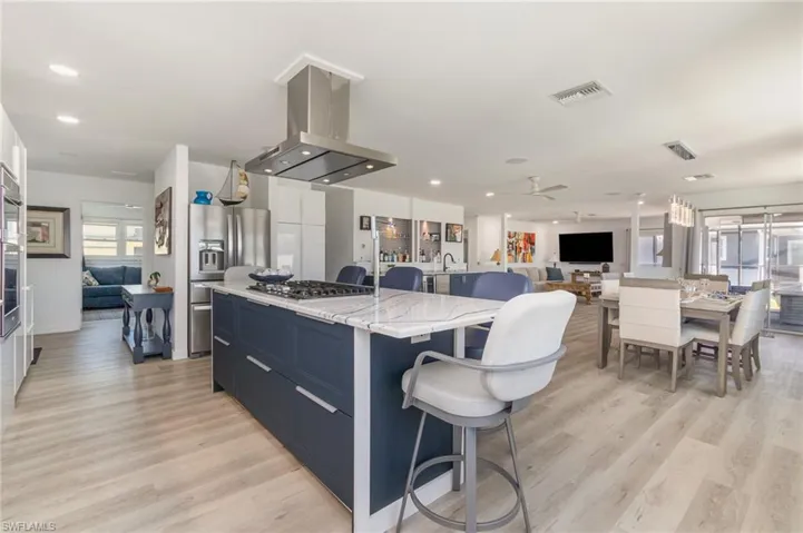 Kitchen with blue cabinetry, a kitchen island, stainless steel fridge with ice dispenser, open floor plan, and a breakfast bar