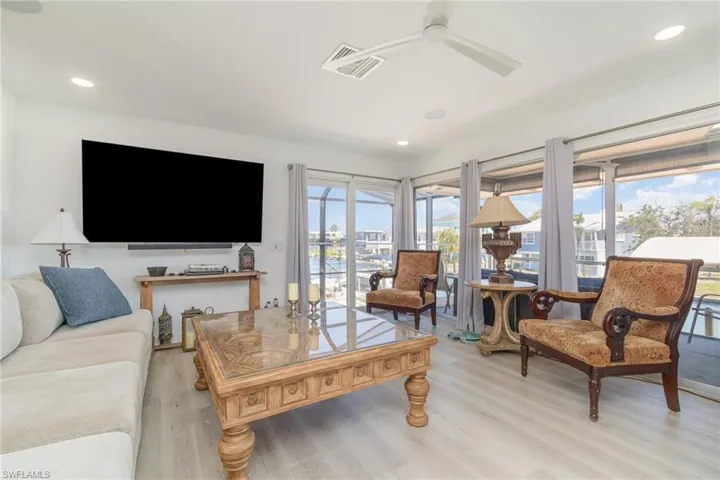 Living area featuring light wood-style floors, ceiling fan, and recessed lighting