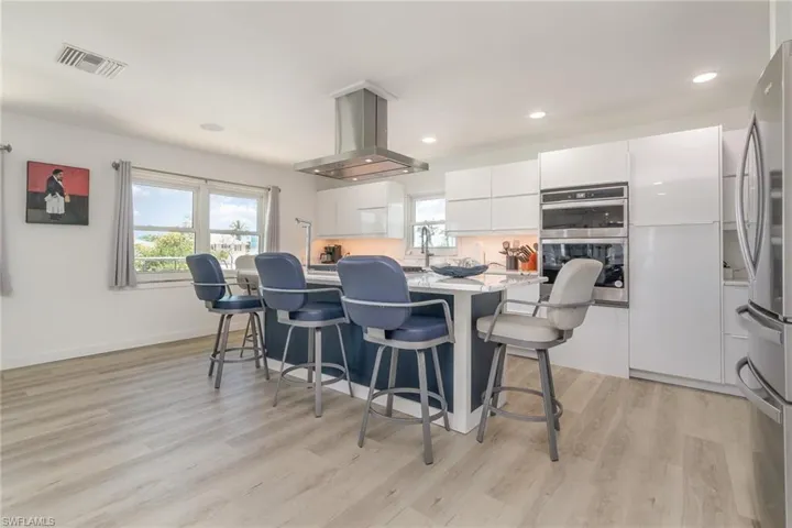 Kitchen with modern cabinets, white cabinetry, appliances with stainless steel finishes, a breakfast bar area, and a center island