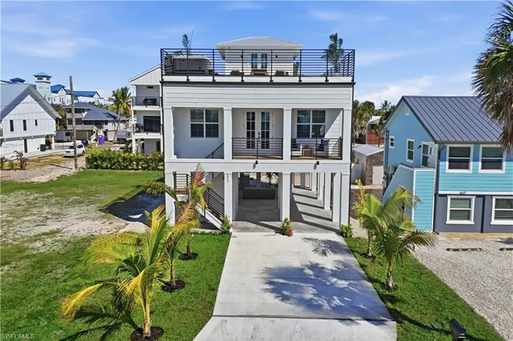 View of front of house featuring driveway, a carport, and a balcony