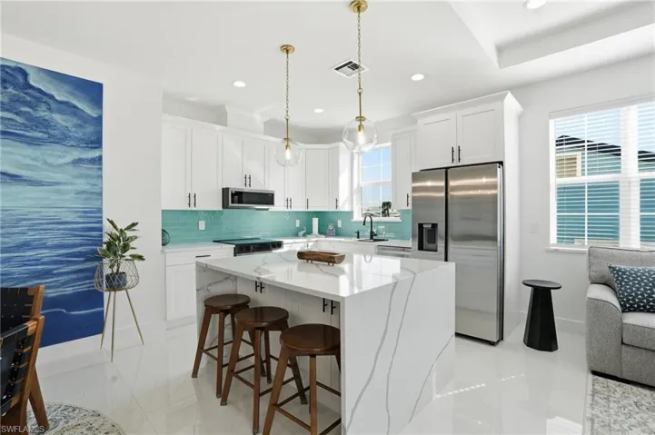 Kitchen featuring a breakfast bar area, stainless steel appliances, a center island, light stone countertops, and pendant lighting