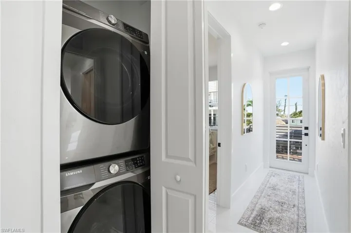 Laundry area featuring stacked washing machine and dryer and recessed lighting