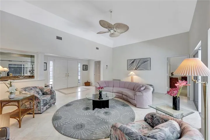 Living room with a ceiling fan, high vaulted ceiling, and visible vents