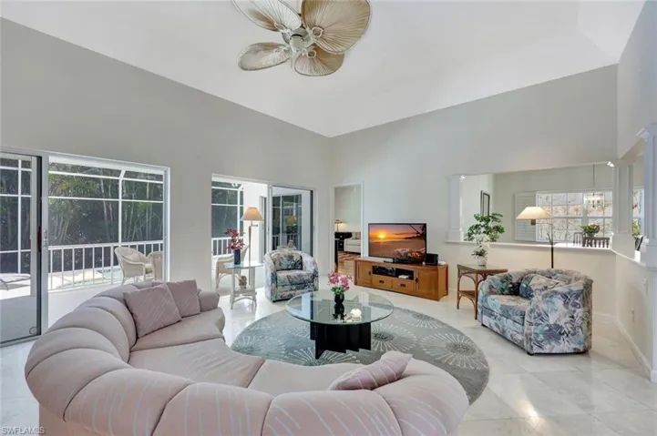 Living area with a ceiling fan, a high ceiling, and a healthy amount of sunlight