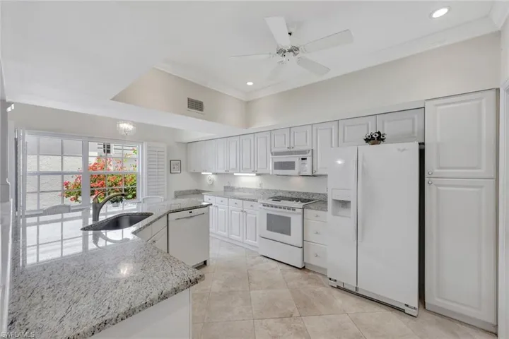 Kitchen featuring visible vents, crown molding, a ceiling fan, white appliances, and a sink