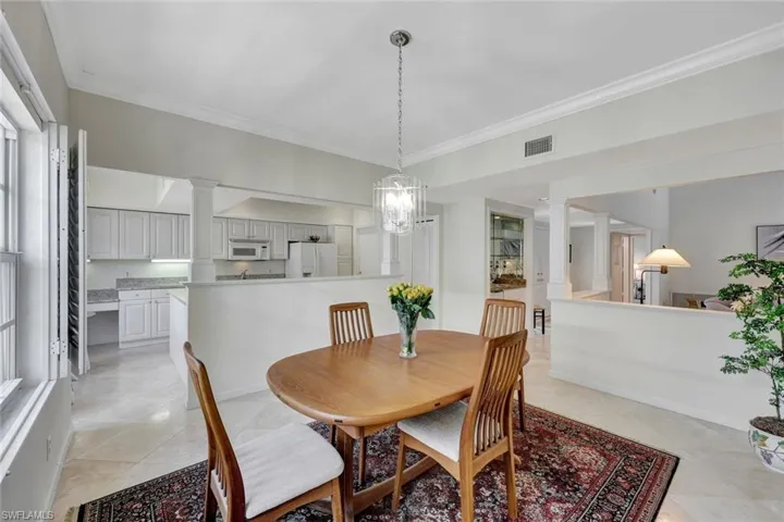 Dining area featuring light tile patterned floors, crown molding, decorative columns, and visible vents