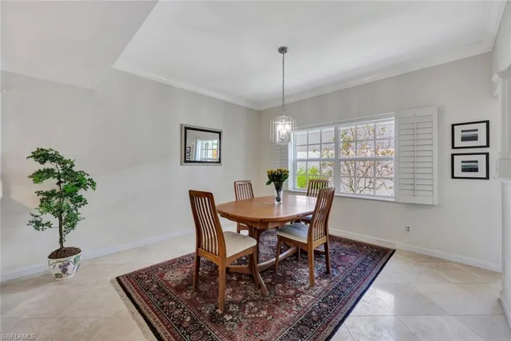 Dining space with crown molding, baseboards, light tile patterned flooring, and a notable chandelier