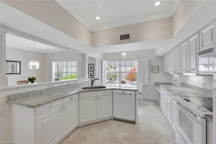 Kitchen with visible vents, crown molding, white appliances, white cabinets, and a sink