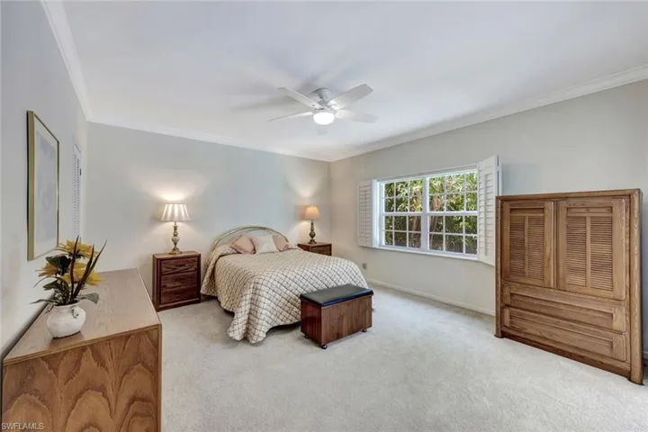 Carpeted bedroom featuring crown molding, a ceiling fan, and baseboards
