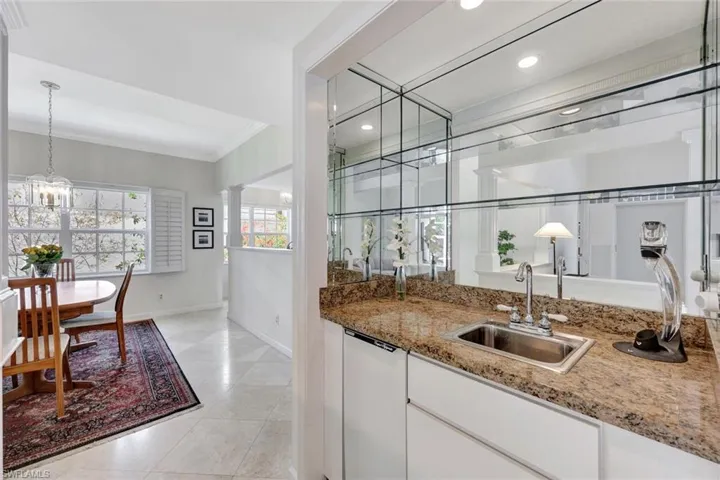 Bar with crown molding, a sink, baseboards, recessed lighting, and light tile patterned flooring