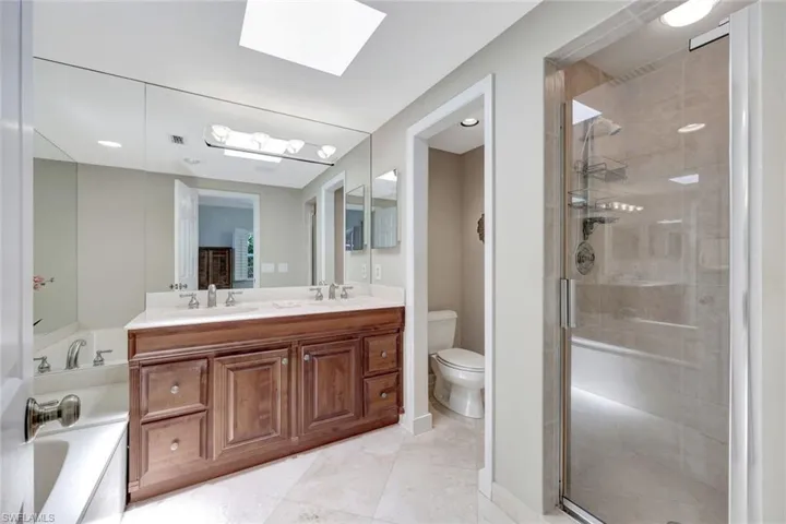Full bathroom with a skylight, a shower stall, a sink, and a bath