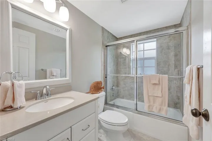 Bathroom featuring vanity, combined bath / shower with glass door, and toilet