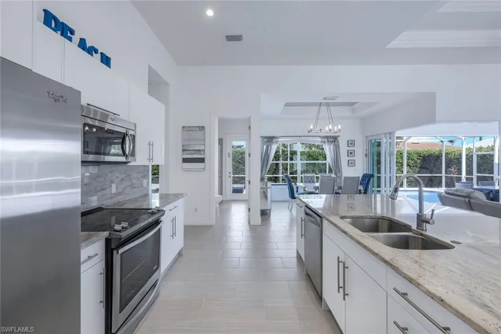 Kitchen featuring white cabinets, stainless steel appliances, decorative light fixtures