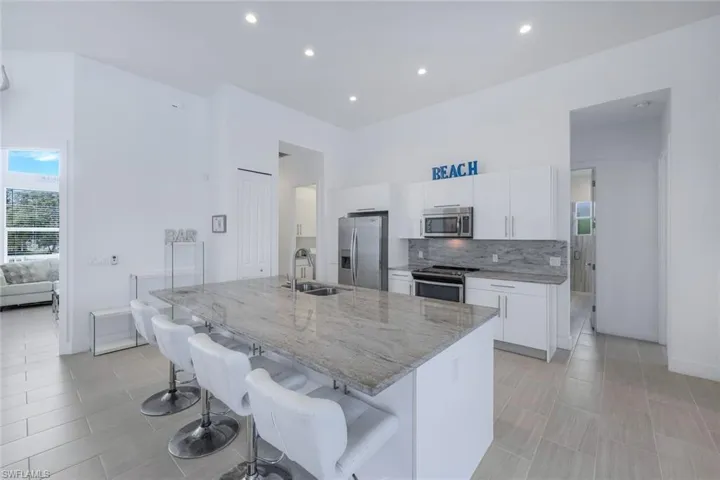 Kitchen featuring white cabinets, stainless steel appliances, decorative light fixtures