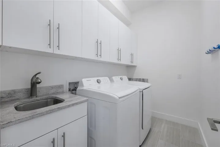 Clothes washing area featuring cabinets, separate washer and dryer, and sink