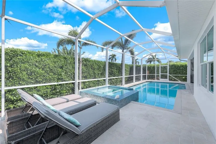 View of pool featuring glass enclosure, an in ground hot tub, and a patio area