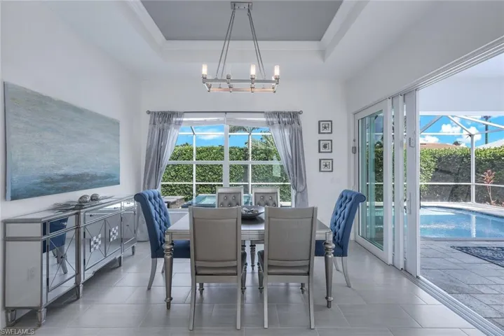 Tiled dining room featuring a tray ceiling and a chandelier