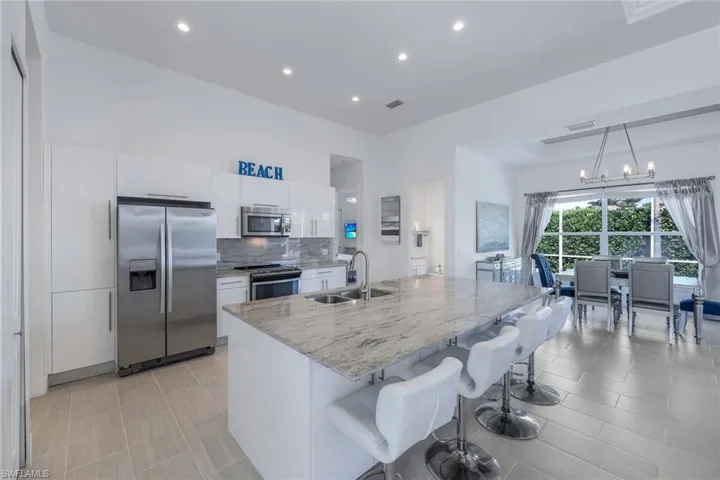 Kitchen featuring white cabinets, stainless steel appliances, decorative light fixtures