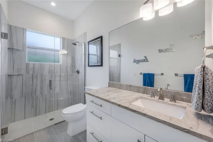 Bathroom with vanity, a shower with shower door, toilet, and tile patterned flooring
