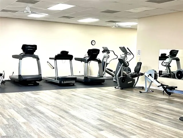 Workout area with a paneled ceiling, ceiling fan, and hardwood / wood-style floors