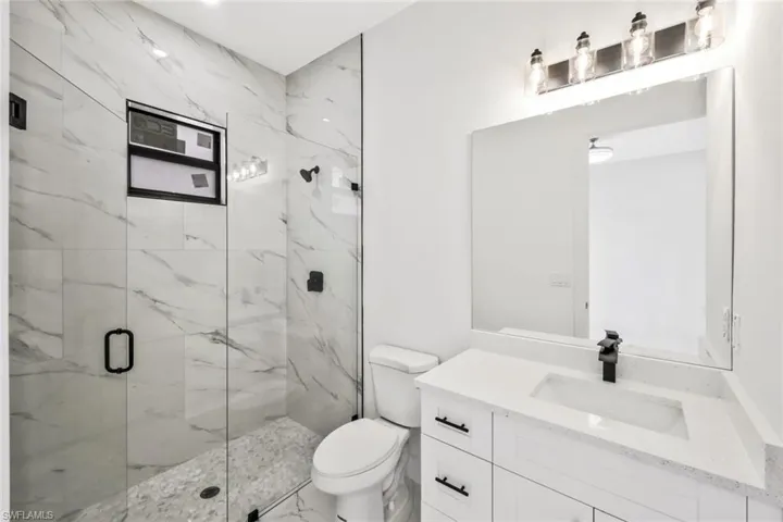 Bathroom featuring a marble finish shower and vanity