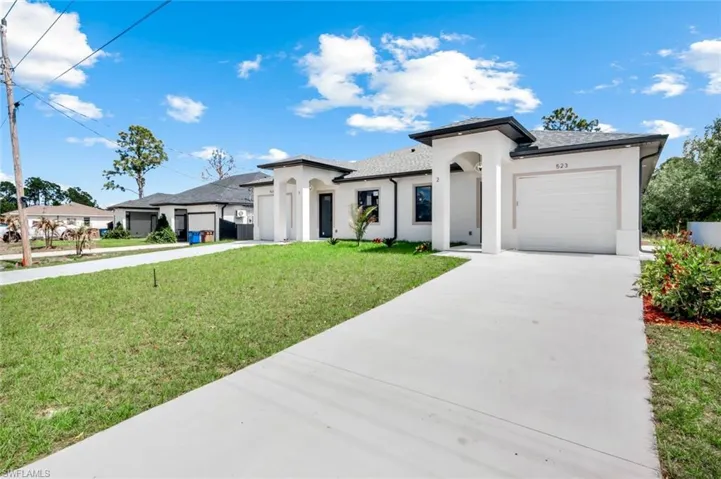 Prairie-style house with an attached garage, stucco siding, a front yard, and driveway