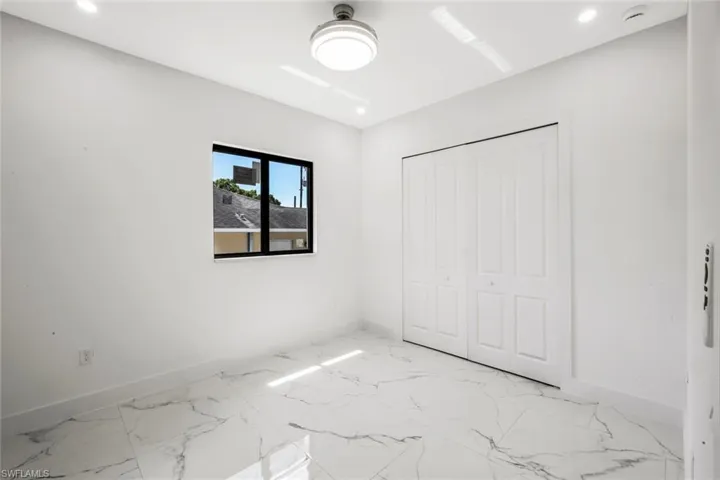 Unfurnished bedroom with light marble finish floors, a closet, and recessed lighting