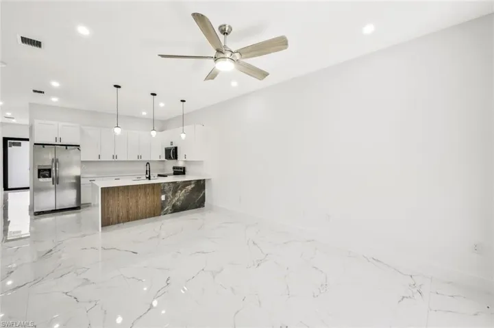 Kitchen featuring stainless steel appliances, open floor plan, a ceiling fan, a peninsula, and hanging light fixtures