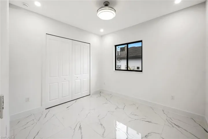 Unfurnished bedroom featuring light marble finish flooring, a closet, and recessed lighting