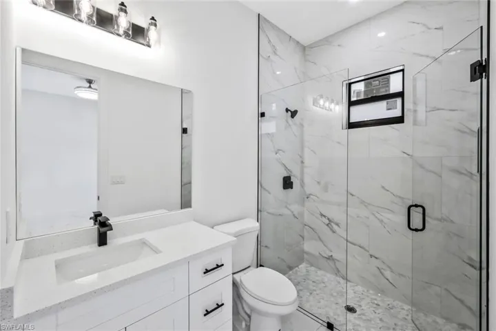 Bathroom featuring vanity and a marble finish shower
